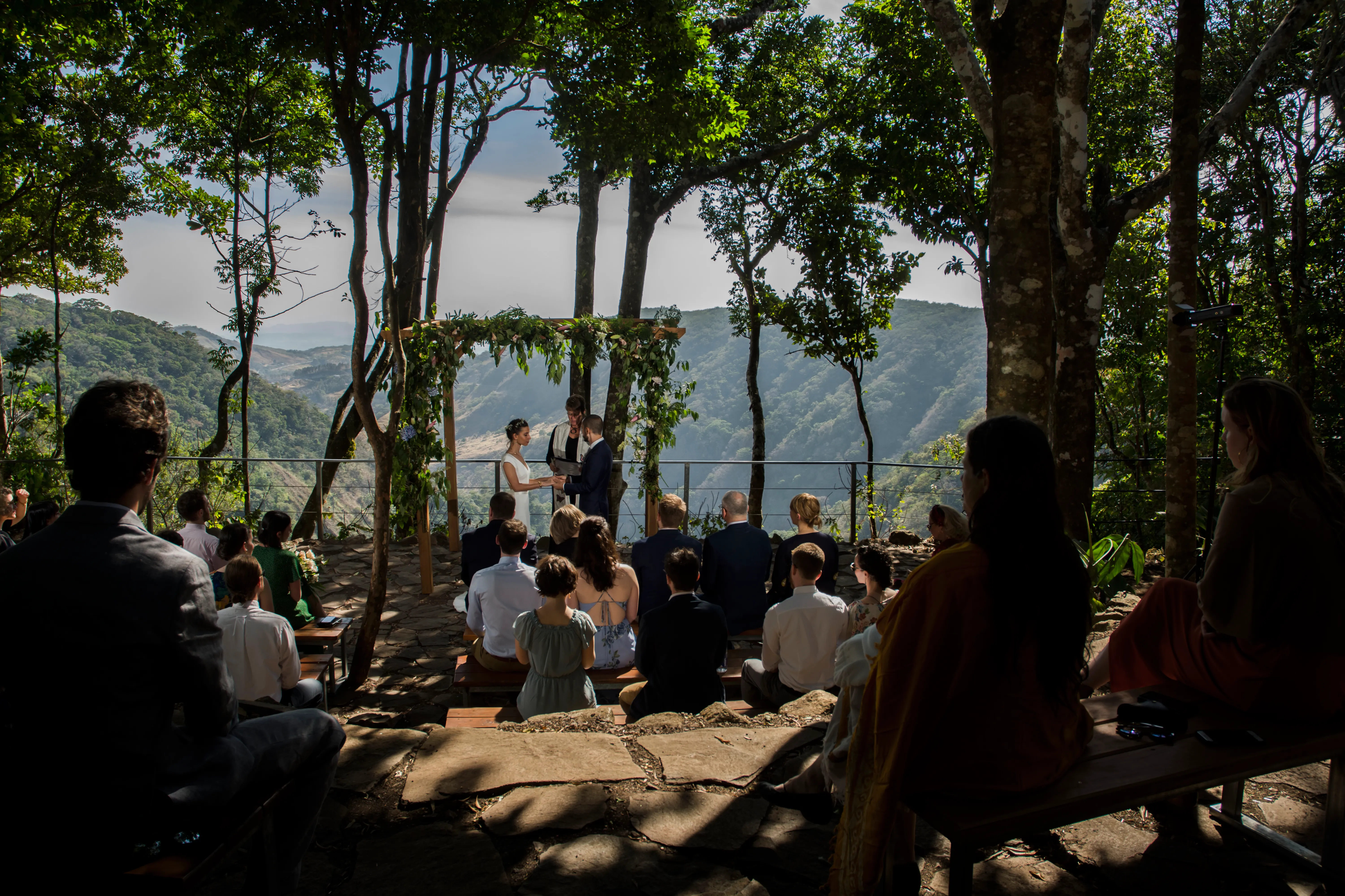Guests and visitors enjoy a wedding at one of our most beautiful viewpoints just beyond our hammock garden. You see mountains and lots of greenery in the background.