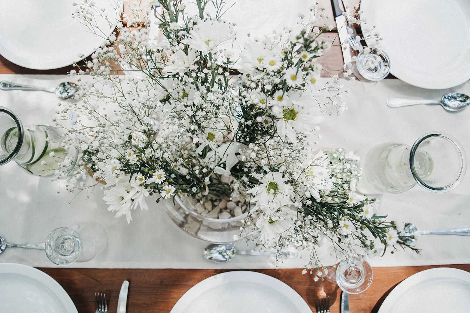 Reception table for a wedding at Valle Escondido with beautiful white flowers and dining plates and silverware.